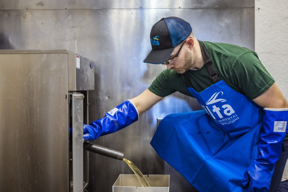 A picture of a Filta Fry engineer draining a deep fat fryer of used cooking oil